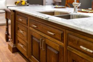 Close-up of a kitchen sink with elegant solid wood cabinets underneath.