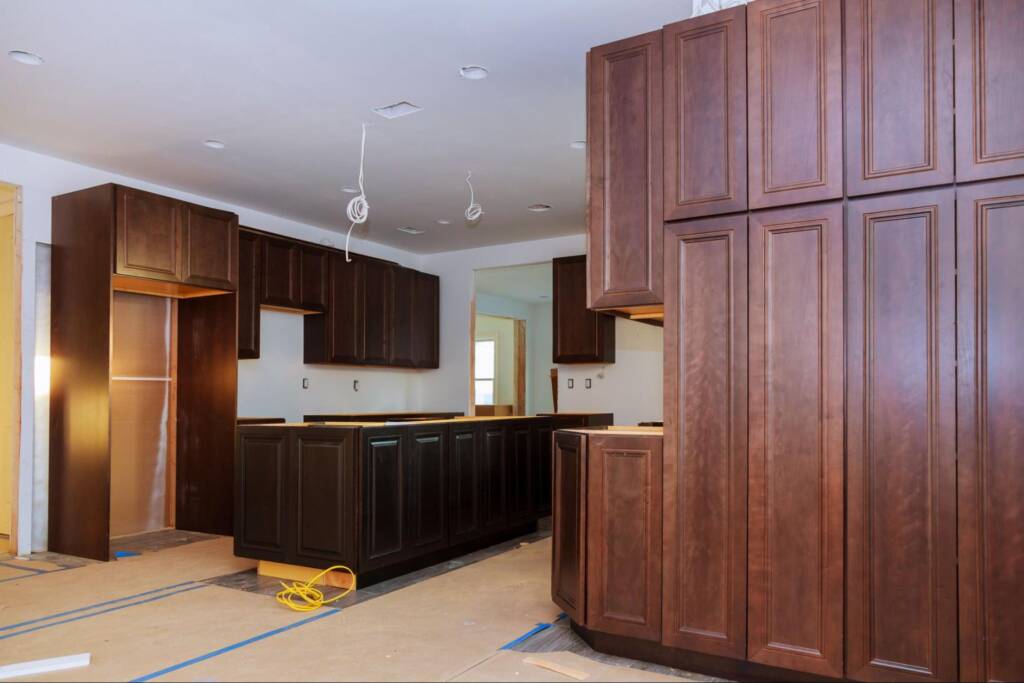 Custom kitchen cabinets in various installation stages with a base island frame positioned in the center.