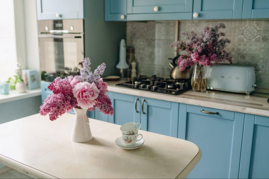 A front view of a modern kitchen with white countertops and blue cabinets.
